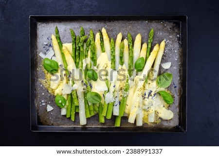 Traditional oven baked white and green asparagus with cheese and sauce hollandaise served as top view on a rustic tray Royalty-Free Stock Photo #2388991337
