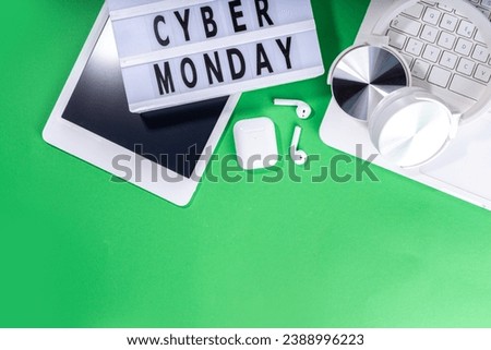 Cyber monday sale background. Simple bright green flat lay with lightbox "Cyber monday", gift boxes, shopping cart, laptop, tablet, headphones top view copy space. Online holiday shopping concept
