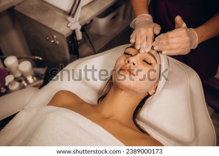 masseur doing facial massage to young woman on massage table on white background. Concept of massage spa treatments. Close-up. High quality photo