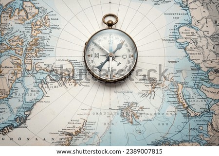 Magnetic old compass on old nord pole map. Travel, geography, history, navigation, tourism and exploration concept background. Retro compass on geography map. Royalty-Free Stock Photo #2389007815