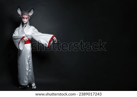 Pretty actress woman with stage makeup, rabbit mask and costume standing on black background. Halloween, carnival, performance and theater concept