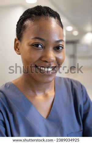 Portrait of happy african american female doctor in hospital corridor. Medicine, healthcare and medical services, unaltered.