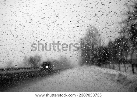 View on winter road and car through wet windshield with rain drops. Background and view              