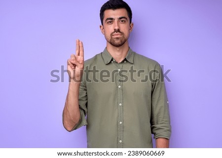 serious handsome man showing letter U u with fingers .the Alphabet in American Sign Language (ASL). isolated blue background closeup portrait