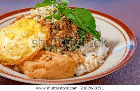 Close picture of Sambel Tumpang with rice, fried egg, some slice cabbage, a toufu, with delicious saouce from tempe and topping with slice of kemangi leaf 