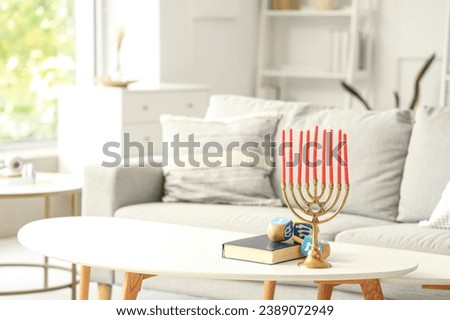 Menorah with Torah and dreidels for Hanukkah on table in living room