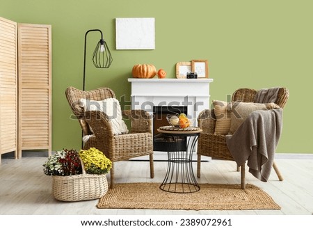 Interior of stylish living room with armchairs, fireplace and pumpkins on coffee table
