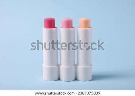 Different lip balms on light blue background Royalty-Free Stock Photo #2389075039