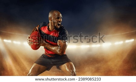 Emotional and motivated African-American young man, rugby player in motions over dark stadium with flashlight and smoke. Concept of professional sport, competition, motivation, game, championship Royalty-Free Stock Photo #2389085233