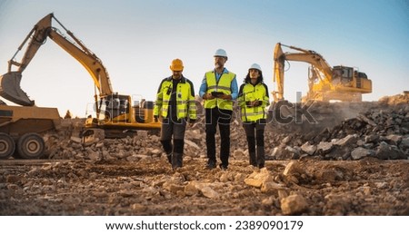 Construction Site With Excavators on Sunny Day: Diverse Team Of Male And Female Specialists Walking And Discussing Real Estate Project. Engineer, Architect, Urban Planner Talking, Using Tablet. Royalty-Free Stock Photo #2389090179