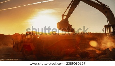 Construction Site On Sunny Evening: Industrial Excavator Loading Rocks Into A Truck. The Process Of Building Apartment Complex. Workers Operating Heavy Machinery To Complete A Real Estate Project. Royalty-Free Stock Photo #2389090629