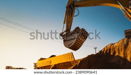 Construction Site On Sunny Evening: Industrial Excavator Loading Sand Into A Truck. The Process Of Building a New Apartment Complex. Workers Operating Heavy Machinery To Complete Real Estate Project Royalty-Free Stock Photo #2389090641