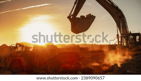 Construction Site On Sunny Evening: Industrial Excavator Loading Rocks Into A Truck. The Process Of Building New Apartment Complex. Workers Operating Heavy Machinery To Complete A Real Estate Project. Royalty-Free Stock Photo #2389090657