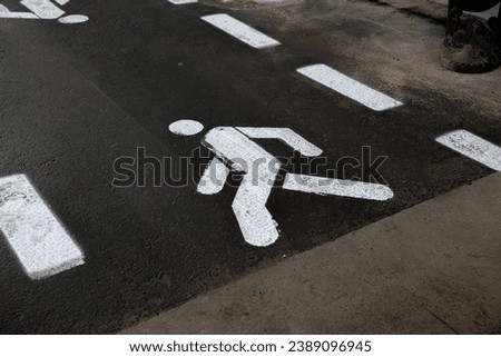 Pedestrian path. The image of a man with paint on the asphalt.