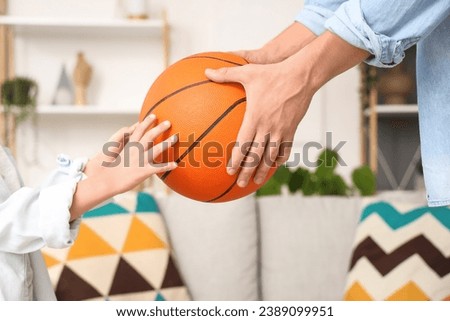 Young man and his little son with ball at home, closeup