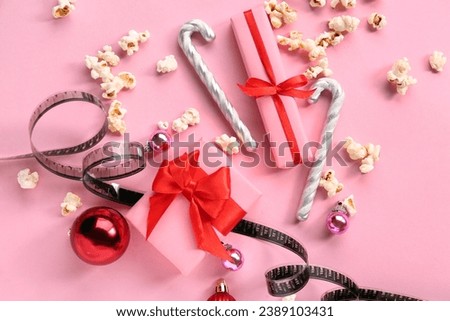 Popcorn with film reel and Christmas decor on pink background