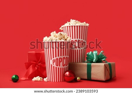 Buckets of popcorn with gifts and Christmas balls on red background