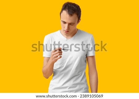 Ill young man with thermometer on yellow background