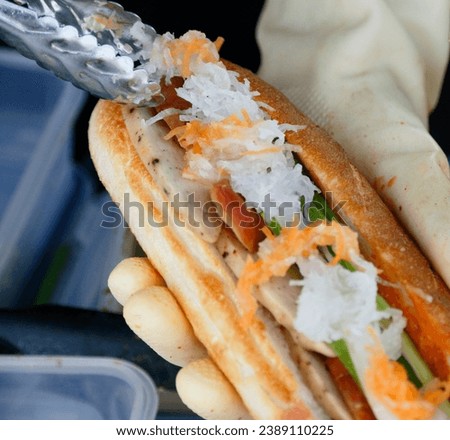 banh mi while preparing, street food Vietnamese sandwich but doing hygiene, short baguette with thin, crisp crust and a soft, airy texture,
Banh mi vendor, Good hygienic preparing street food sandwich