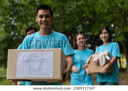 Happy young Asian students diverse volunteers hold donate box and toys for charity to share children and orphanages, a charity for sustainability. Volunteer work lifestyle and social cooperation Royalty-Free Stock Photo #2389117247