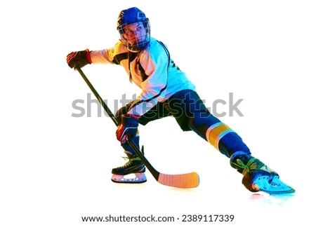 Motivation to win. Young girl, hockey player in helmet and uniform, training, playing against white background in neon light. Concept of professional sport, competition, game, action, hobby