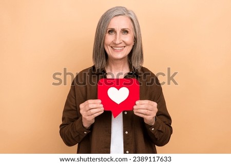 Photo of positive pretty lady beaming smile arms hold paper like notification card isolated on beige color background