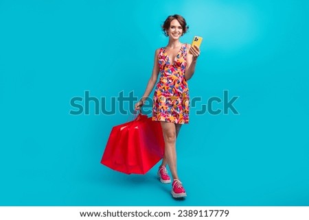 Full size photo of charming woman dressed colorful clothes walk with new outfit order taxi on smartphone isolated on blue color background