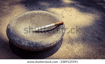 "This is a photo of a cigarette placed on top of a bowl of spices, symbolizing the choice some men make to prioritize buying cigarettes despite knowing their spouse's kitchen spices are running out." Royalty-Free Stock Photo #2389125591