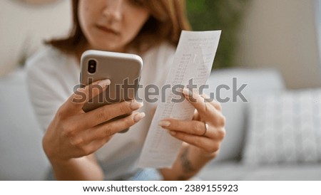 Young woman accounting supermarket ticket with smartphone at home