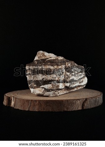 Raw stone of nature, against the black background, wooden base, I have the hobby of collecting stones from nature, for each stone its qualities and attributes, are beautiful and pure like clouds