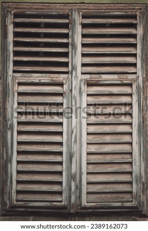 Old wooden window with shutters, country house with old cracked concrete. closed wooden window frame, old cracked paint. vintage window with closed shutters. wooden window shutter and peeling paint.
