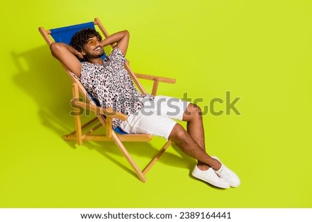 Full body photo of handsome young man enjoy weekend sunbed dressed stylish pink leopard print clothes isolated on yellow color background