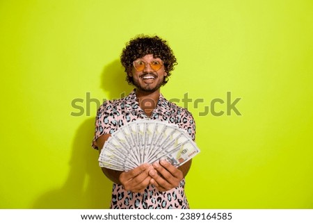Photo portrait of attractive young man money fan excited dressed stylish pink leopard print clothes isolated on yellow color background