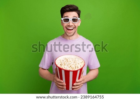 Portrait of impressed person with stubble wear violet t-shirt in 3d glasses hold popcorn watch film isolated on green color background