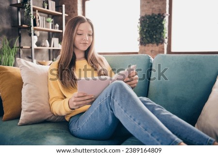 Photo of teen girl enjoying her book she bought in bookstore relaxed sitting at living room indoors isolated on windows daylight background Royalty-Free Stock Photo #2389164809