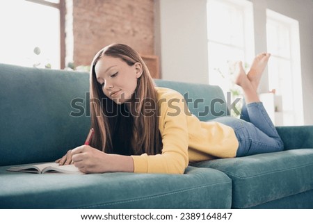 Photo of pleasant clever adorable girl with straight hairdo dressed yellow pullover lay on couch at home write diary inside indoors Royalty-Free Stock Photo #2389164847
