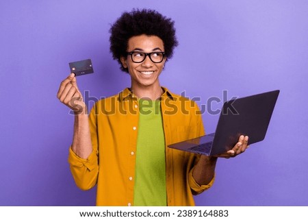 Photo of funny cheerful man wear trendy clothes hold credit debit card look empty space offer isolated on violet color background