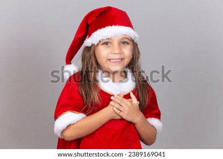 Adorable little girl with hand on chest in gratitude concept dressed in Christmas outfit