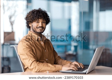 Portrait of young successful businessman inside office at workplace, hispanic smiling and looking at camera, male programmer happy with achievement results.