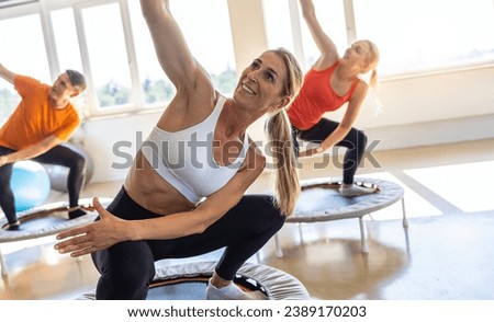 Woman leading a trampoline fitness class with others following the exercise routine Royalty-Free Stock Photo #2389170203