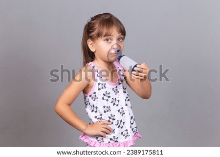 sick girl makes inhalation on gray background with copy space. Girl doing inhalation with nebulizer. Child Asthma Inhaler Inhalation Nebulizer Steam Sick Cough
