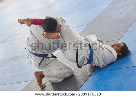 Whos in control here. Full length shot of two young martial artists practicing jiu jitsu in the gym. Royalty-Free Stock Photo #2389176513