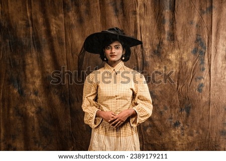 beautiful female model wearing a bege dress and a black hat vintage look