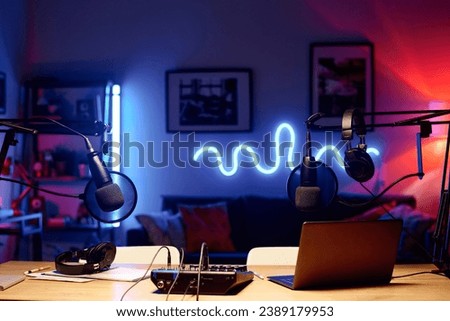 Laptop surrounded by microphones with headphones and soundboard