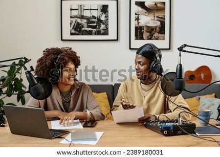 Happy young woman looking at male radio presenter with paper