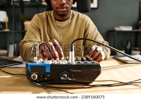 Focus on hands of young male host turning consoles of soundboard