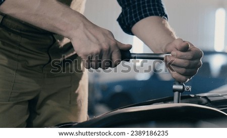 Hands of an auto mechanic close-up working on a car engine in a car repair shop. Ratchet wrench Royalty-Free Stock Photo #2389186235