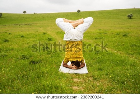 A man does yoga in nature, in the mountains on green grass. The concept of sports, recreation, and meditation.Healthy lifestyle
