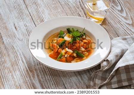 Minestrone white bean soup with seasonal summer vegetables, healthy vegan meal,  rustic wooden table, close up