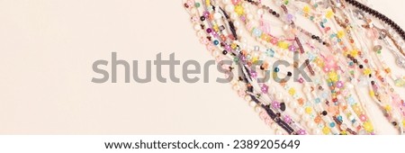 Banner with chains of beads, pearls and natural stones on a beige background. 